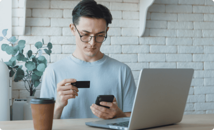 クレカとパソコン画面を見比べる男性