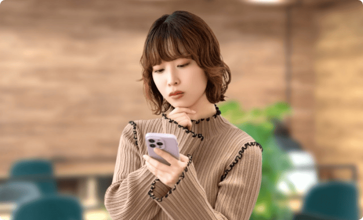 スマホを見ながら悩む女性