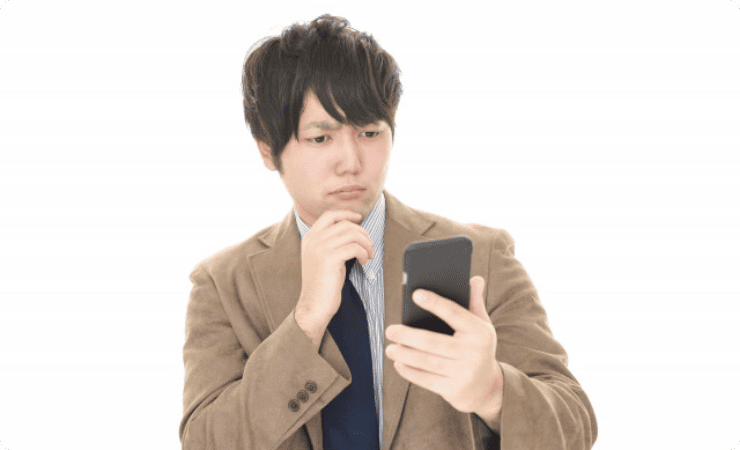 険しい顔でスマホを見る男性